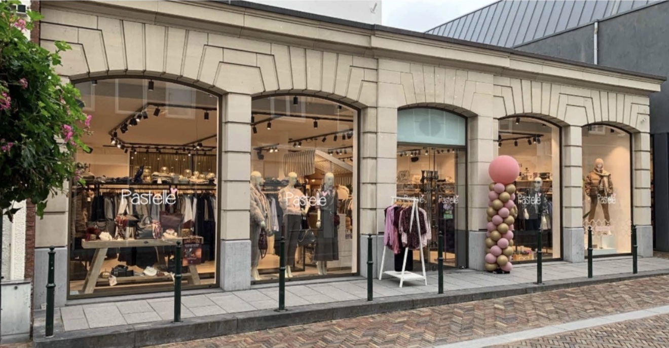 De gevel van Pastelle Wassenaar aan de Langstraat, met verlichte etalages achter ronde bogen